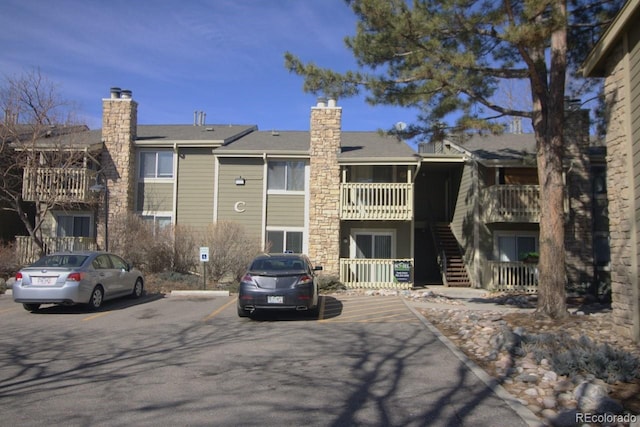 view of building exterior with uncovered parking and stairs