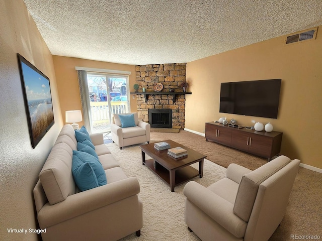 carpeted living area with a fireplace, a textured ceiling, visible vents, and baseboards