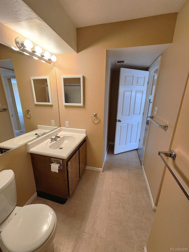 bathroom featuring vanity, visible vents, toilet, tile patterned floors, and baseboards