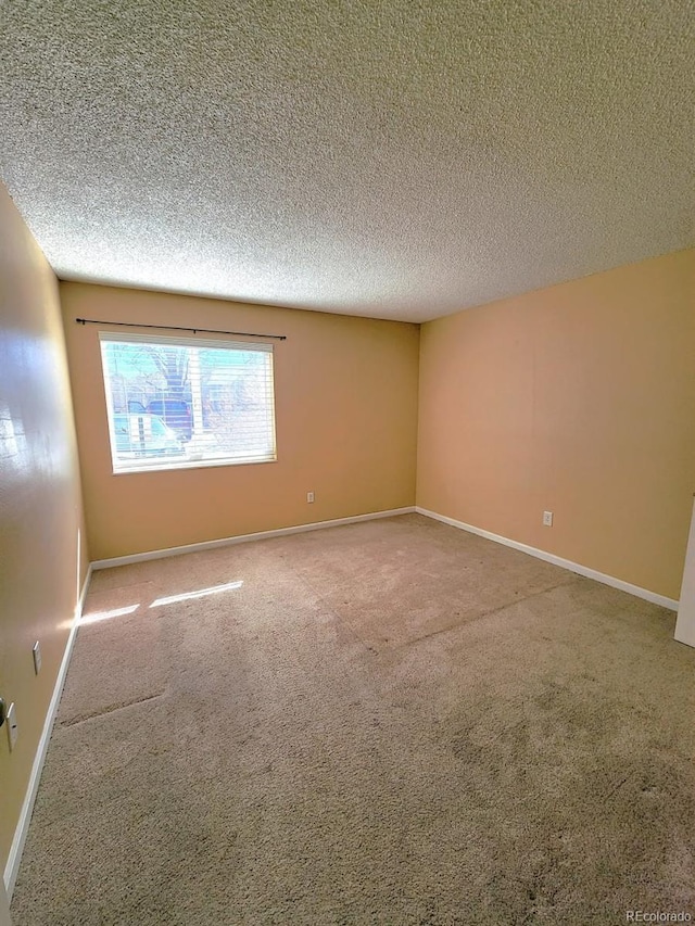 carpeted spare room with a textured ceiling and baseboards