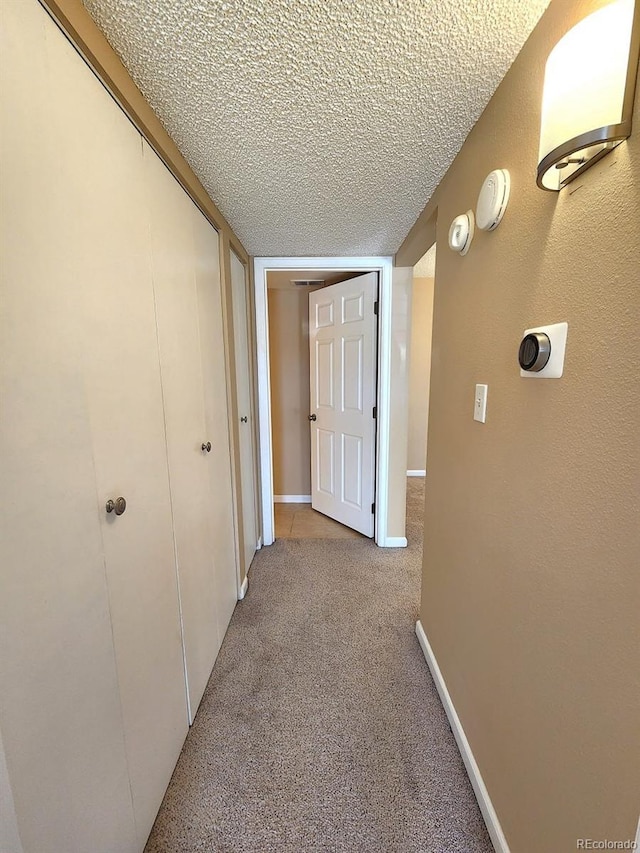 hall featuring a textured ceiling and light carpet