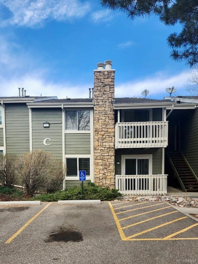view of property featuring uncovered parking and stairway