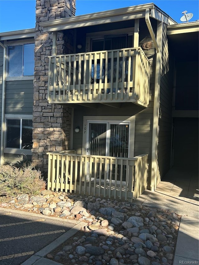 rear view of property with stone siding and a balcony