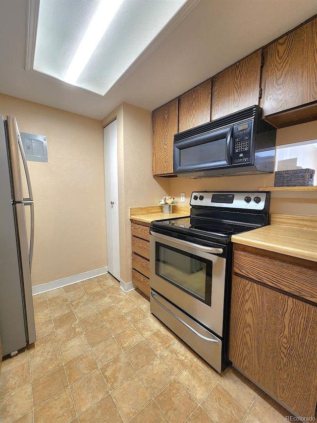 kitchen with brown cabinetry, light countertops, baseboards, and stainless steel appliances