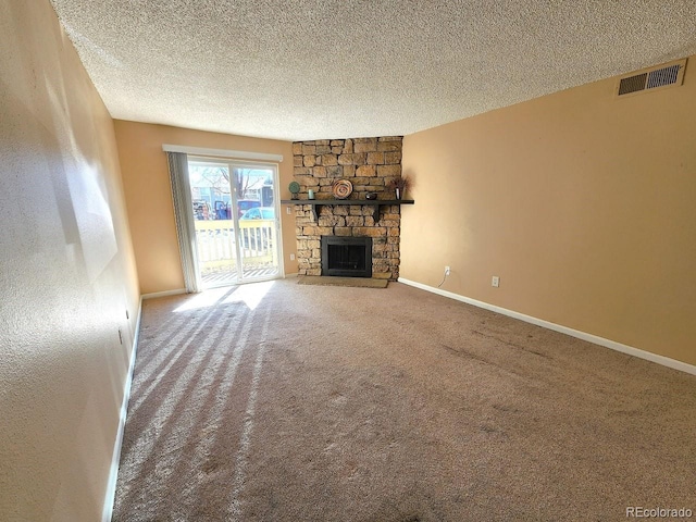 unfurnished living room with visible vents, baseboards, a textured ceiling, a fireplace, and carpet flooring