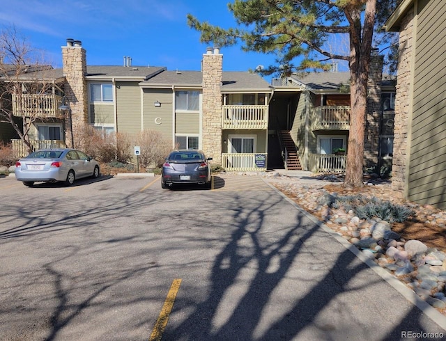 exterior space with stairway, uncovered parking, and a chimney