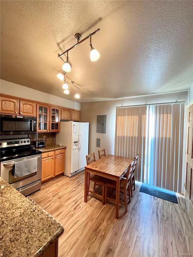 kitchen featuring track lighting, a textured ceiling, stainless steel appliances, and light hardwood / wood-style floors