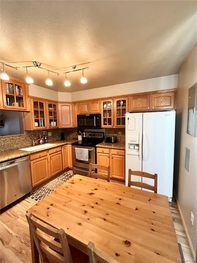 kitchen with a textured ceiling, light hardwood / wood-style flooring, backsplash, stainless steel appliances, and sink