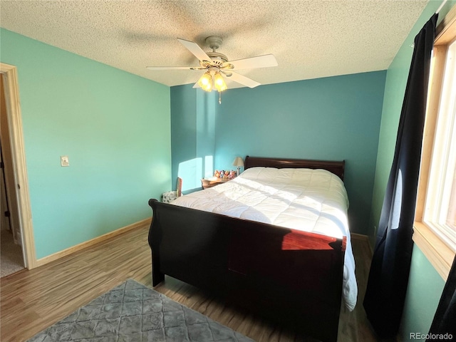 bedroom with a textured ceiling, ceiling fan, and wood-type flooring