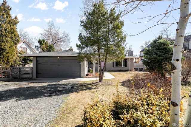 ranch-style home featuring a garage, brick siding, fence, driveway, and a chimney