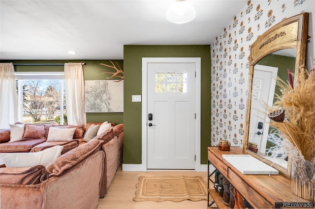 foyer with wallpapered walls, plenty of natural light, and light wood-style floors