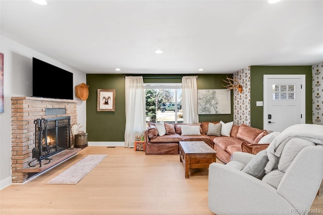 living area featuring baseboards, light wood-type flooring, a brick fireplace, and recessed lighting