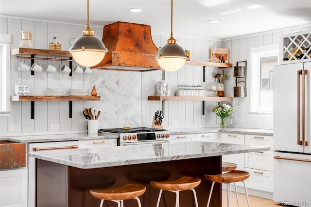 kitchen with white appliances, tasteful backsplash, custom range hood, white cabinetry, and open shelves