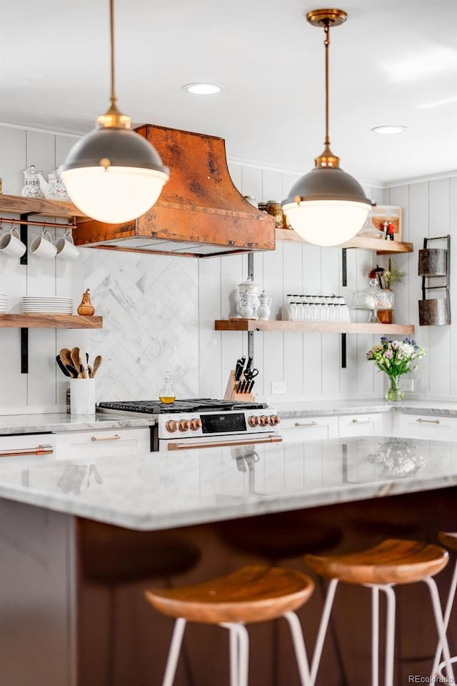 kitchen featuring tasteful backsplash, light stone counters, a kitchen breakfast bar, open shelves, and gas stove