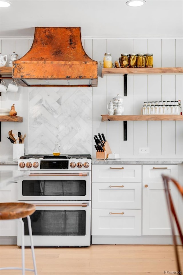 kitchen with range with two ovens, open shelves, tasteful backsplash, custom range hood, and white cabinets