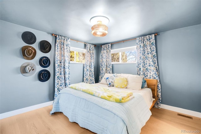 bedroom featuring wood finished floors, visible vents, and baseboards