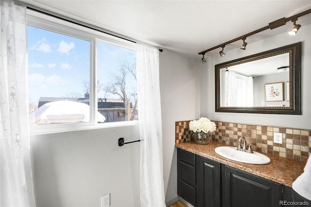 bathroom with rail lighting, vanity, and decorative backsplash