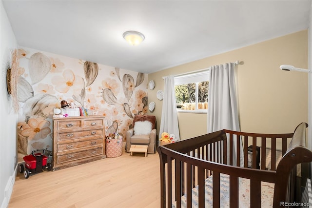 bedroom with a nursery area and wood finished floors