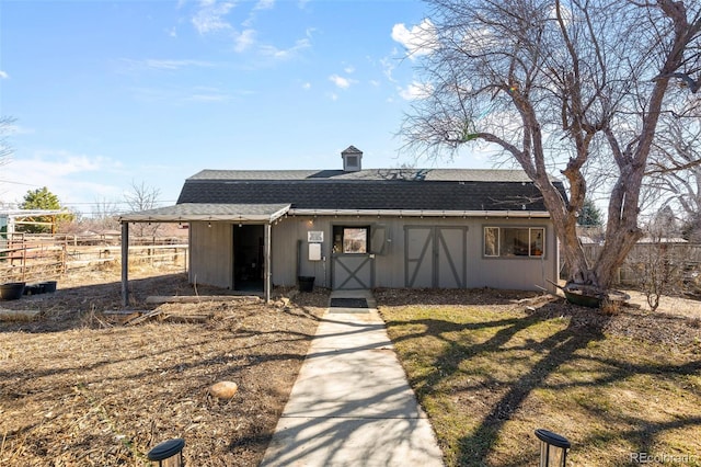 view of front facade featuring fence, an outdoor structure, and roof with shingles