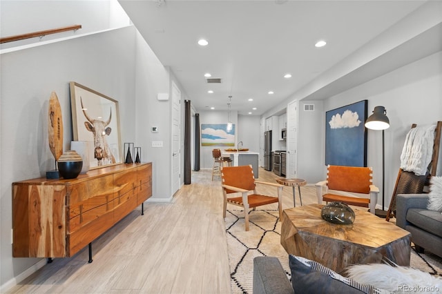 living room featuring sink and light hardwood / wood-style flooring