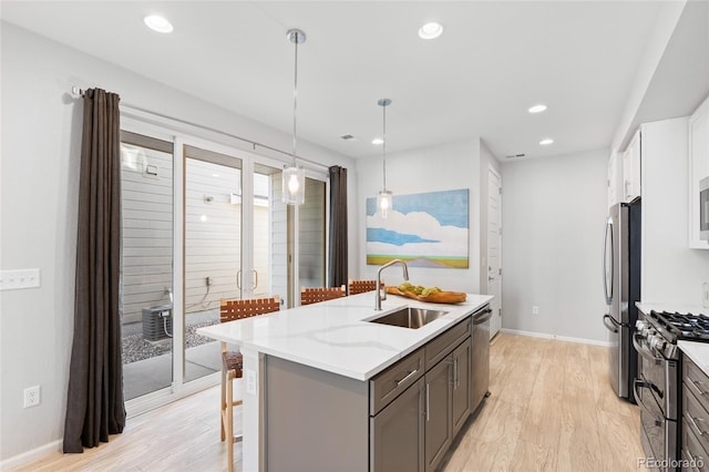 kitchen featuring sink, hanging light fixtures, stainless steel appliances, light stone countertops, and white cabinets