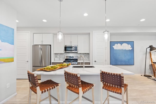 kitchen featuring pendant lighting, sink, appliances with stainless steel finishes, tasteful backsplash, and white cabinets