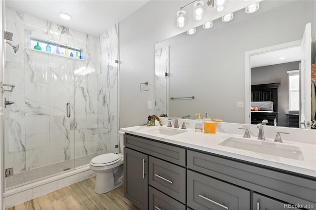 bathroom featuring hardwood / wood-style flooring, vanity, toilet, and a shower with shower door