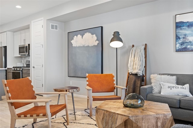 living area with light wood-type flooring, baseboards, visible vents, and recessed lighting