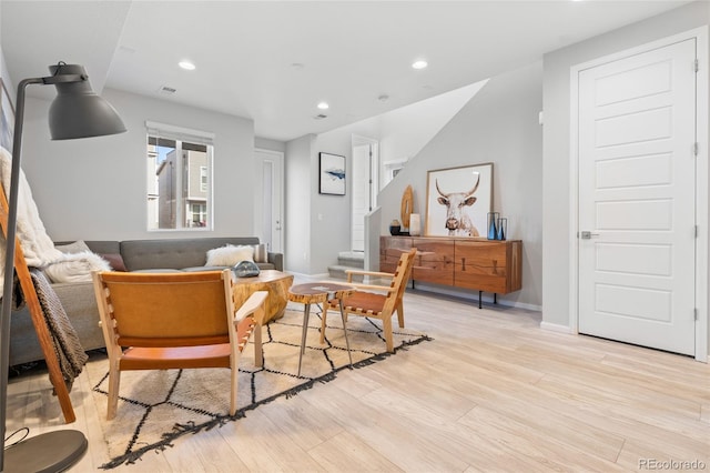 living area featuring baseboards, stairway, light wood-type flooring, and recessed lighting