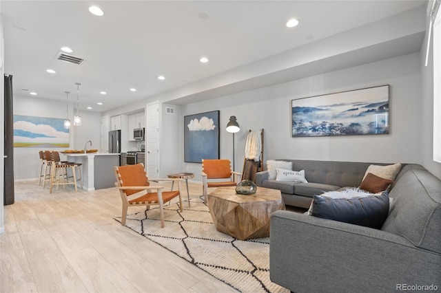 living area with light wood finished floors, baseboards, visible vents, and recessed lighting