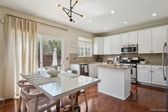 16164 E Hinsdale Ave, Aurora, CO 80016 - kitchen with decorative backsplash, white cabinets, appliances with stainless steel finishes, and a kitchen island