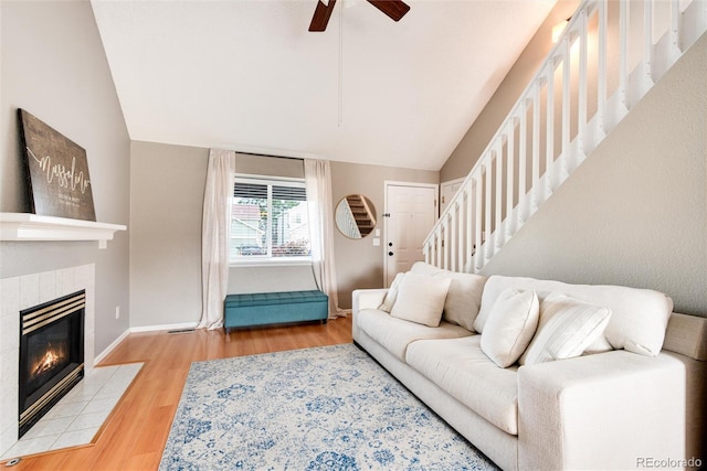 living room featuring a tile fireplace, ceiling fan, light hardwood / wood-style flooring, and lofted ceiling