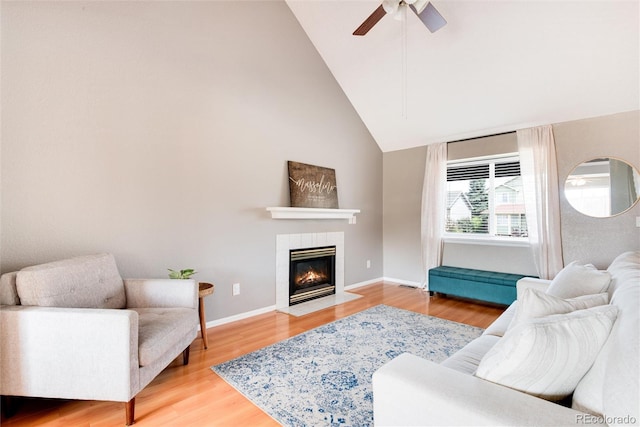 living room with a tiled fireplace, ceiling fan, lofted ceiling, and hardwood / wood-style flooring