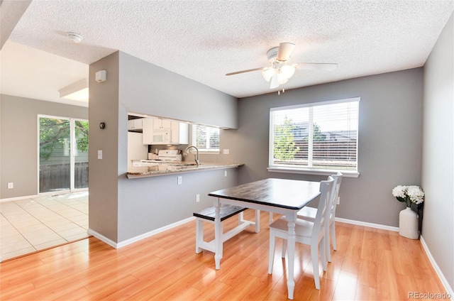 dining room featuring a textured ceiling, light hardwood / wood-style floors, ceiling fan, and sink