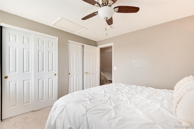 carpeted bedroom with a textured ceiling, ceiling fan, and two closets