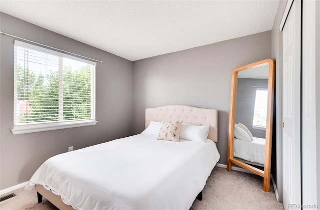 carpeted bedroom with a textured ceiling and a closet