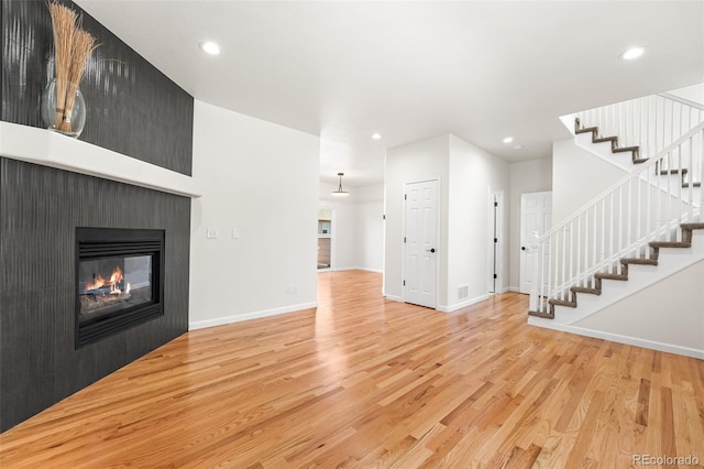 7600 W Coal Mine Ave Unit B, Littleton, CO 80123 - unfurnished living room with light wood-style flooring, stairs, recessed lighting, and a multi sided fireplace