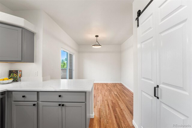 7600 W Coal Mine Ave Unit B, Littleton, CO 80123 - kitchen featuring gray cabinets, light wood finished floors, a peninsula, light stone countertops, and decorative light fixtures