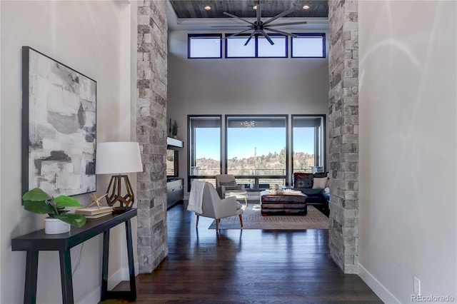 living room with dark wood-type flooring, a high ceiling, and ceiling fan