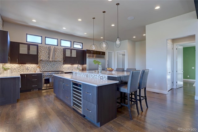 kitchen with decorative light fixtures, wall chimney exhaust hood, a spacious island, and dark hardwood / wood-style floors