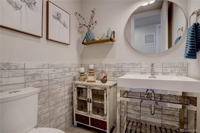 bathroom with tile walls and toilet