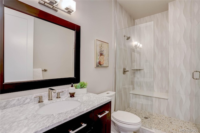 bathroom with toilet, a shower with shower door, and vanity