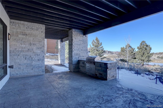 snow covered patio with grilling area and an outdoor kitchen