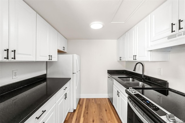 kitchen with light wood-style flooring, a sink, under cabinet range hood, white cabinetry, and appliances with stainless steel finishes