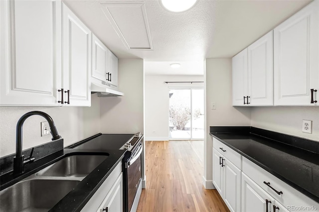 kitchen featuring light wood-type flooring, under cabinet range hood, a sink, white cabinets, and stainless steel electric range oven