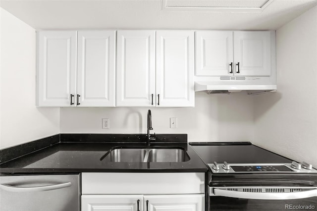 kitchen with under cabinet range hood, dark stone counters, appliances with stainless steel finishes, white cabinetry, and a sink