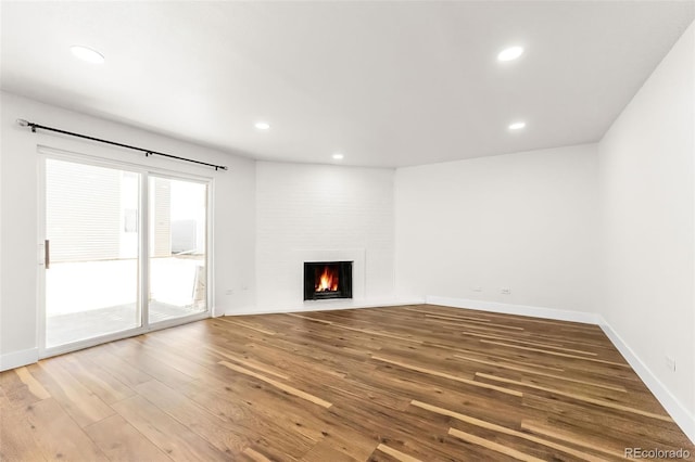 unfurnished living room featuring recessed lighting, a fireplace, baseboards, and wood finished floors