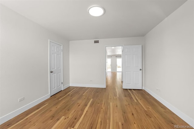 unfurnished room featuring visible vents, baseboards, and light wood finished floors