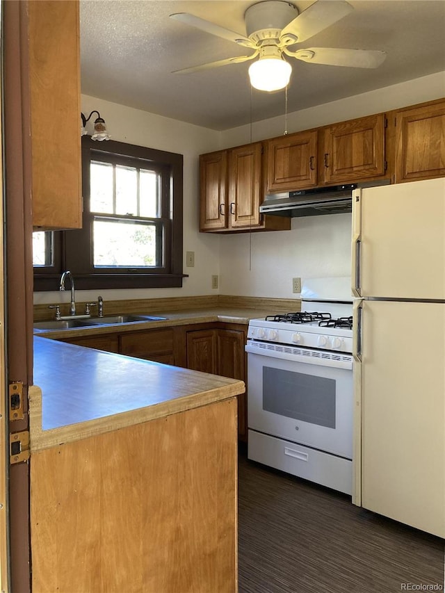 136 Cave Ave, Manitou Springs, CO 80829 - kitchen with white appliances, under cabinet range hood, brown cabinetry, ceiling fan, and a peninsula