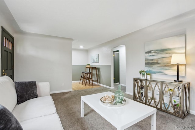 carpeted living area featuring arched walkways, baseboards, and recessed lighting